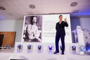 Wojciech Kardyś na scenie w tle slajd o dezinformacji